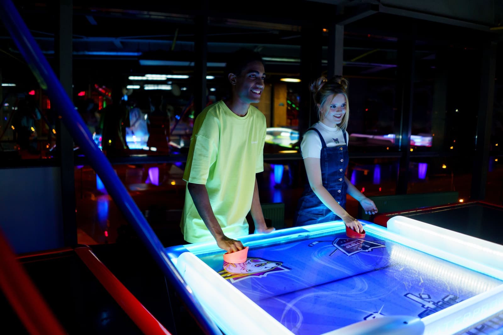 An air hockey table with a lit playfield in a home game room