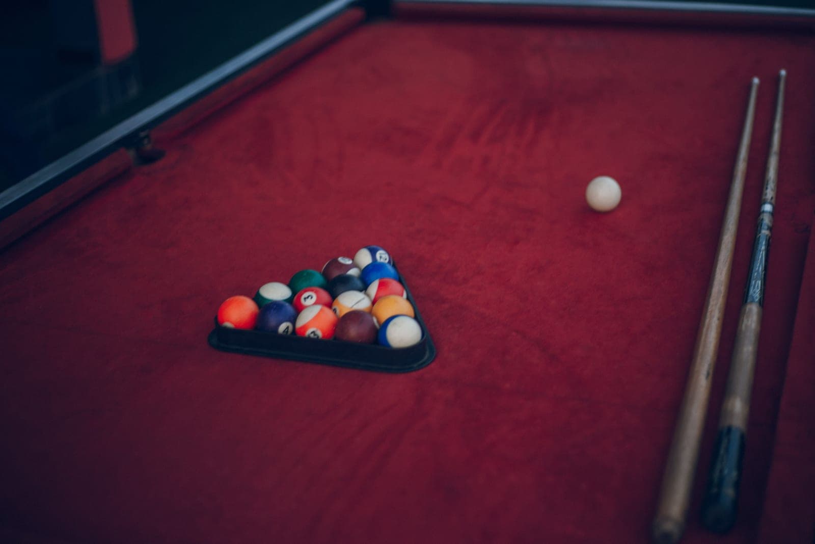 Two-piece pool cues standing in a wall rack beside a table