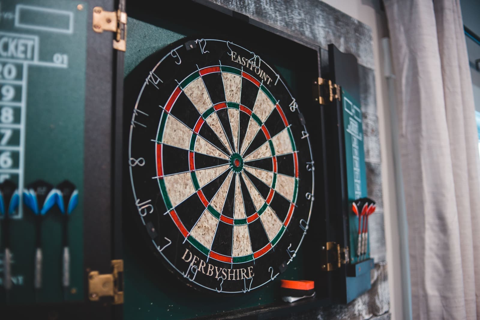 Brightly colored soft-tip darts beside an electronic dart board