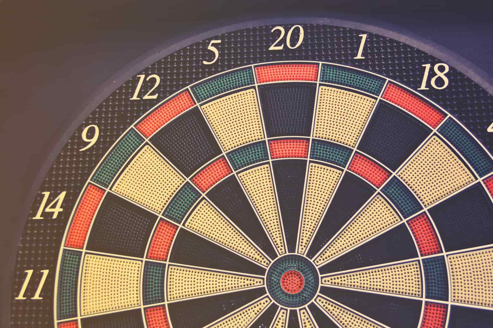 Three steel-tip darts grouped in the treble bed of a sisal dartboard