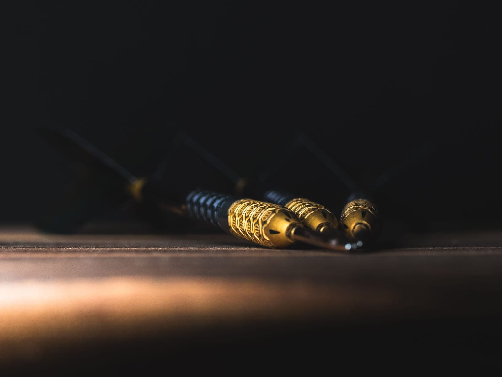 A steel-tip dart barrel beside its flights and stems