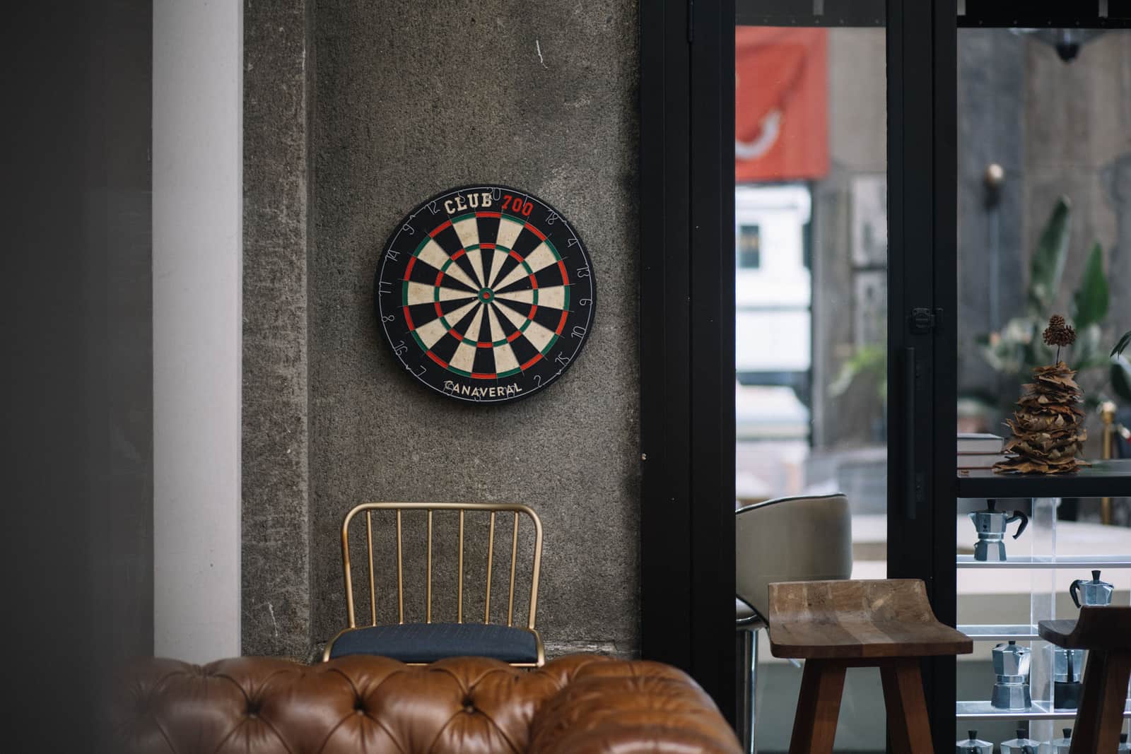 A bristle dartboard mounted on a concrete wall in a daylit room