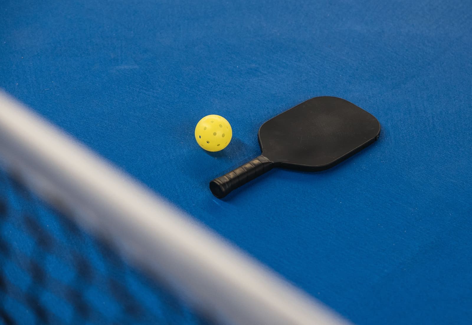 A paddle and ball resting on a table tennis surface near the net