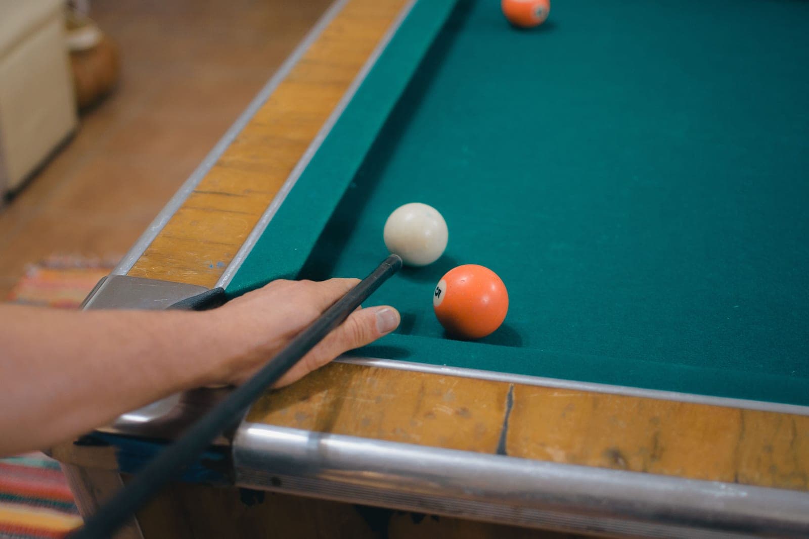 A wood-railed pool table in a low-lit room