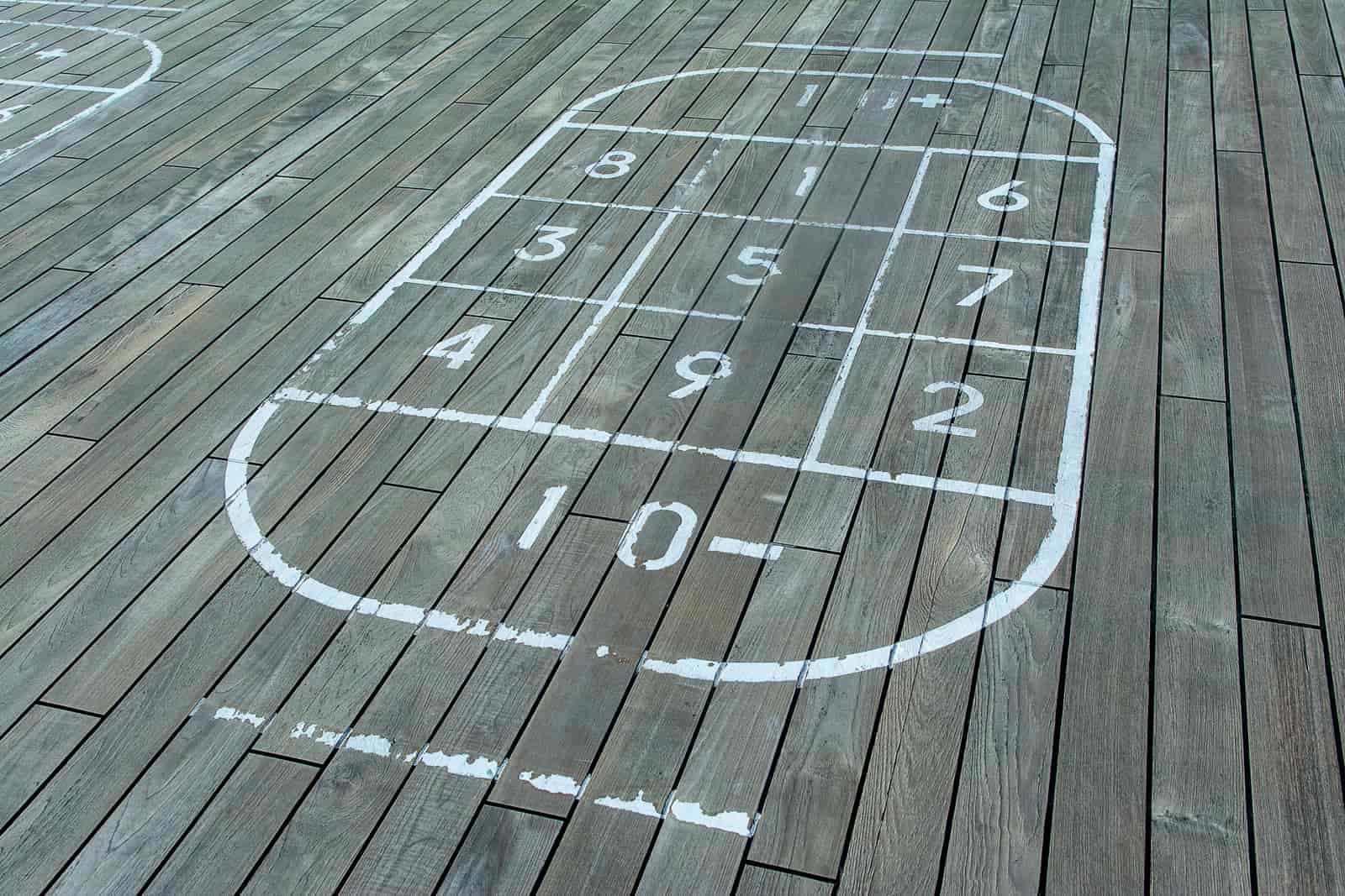 A long wooden shuffleboard playfield under warm light