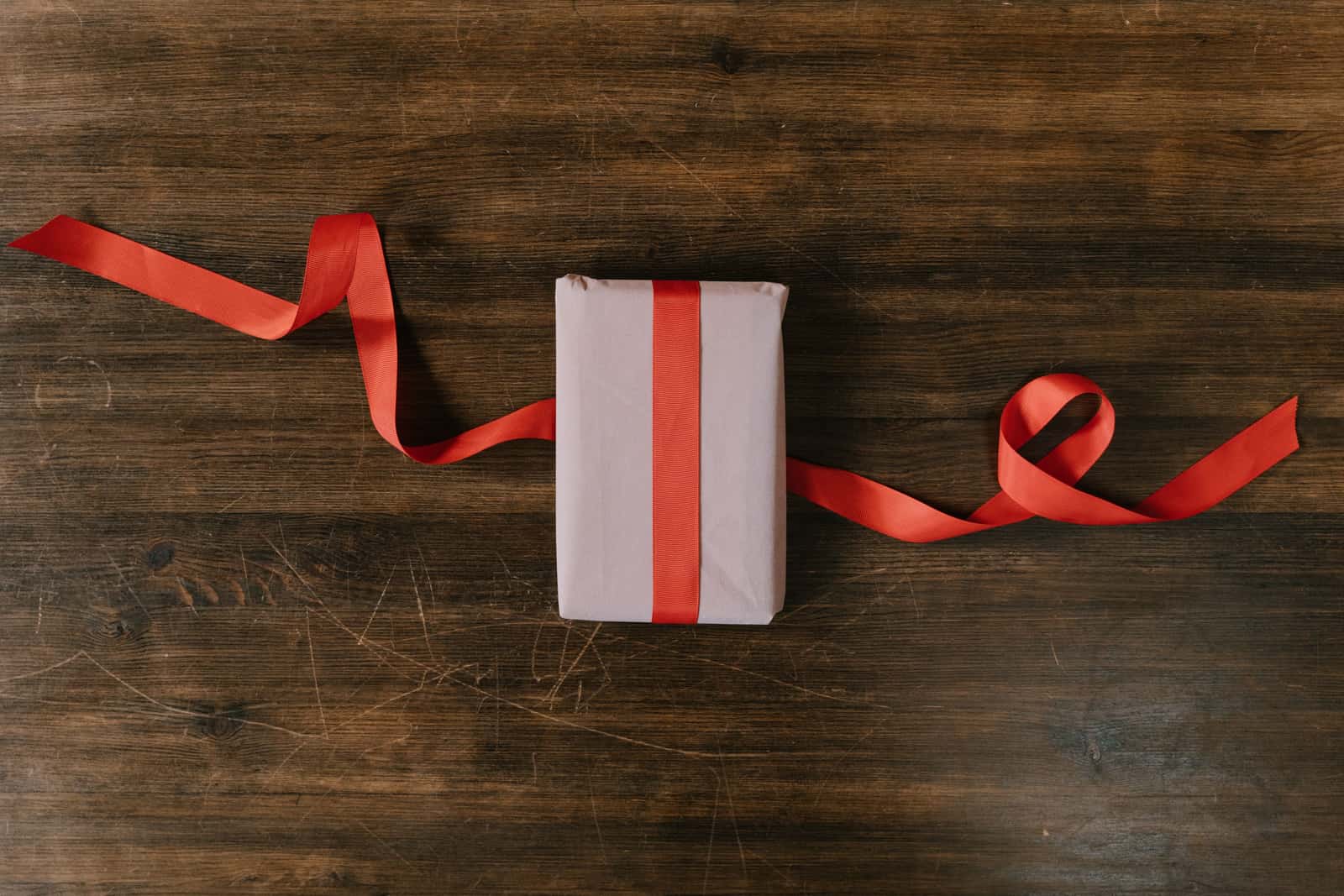A wrapped gift sitting on a dark wooden surface in a low-lit room